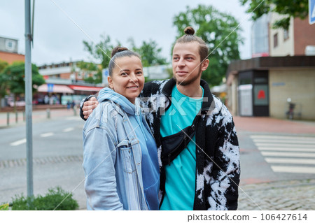 Portrait of 18, 19 year old son embracing with his mother, outdoor 106427614