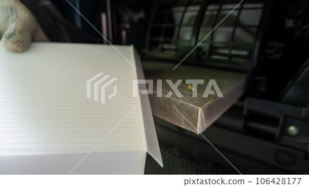 A mechanic changes the cabin air filter of a car. 106428177