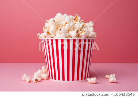Popcorn in red and white striped bucket isolated on pink background 106428546