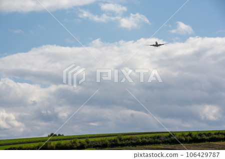 Jet airliner flying through green upland fields Jet airliner flying through green upland fields 106429787