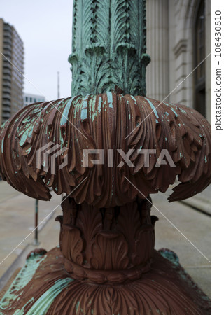 Cast iron, forged antique street lamp with paint peeling off over time in front of the City Hall Cast iron, forged antique street lamp with paint peeling off over time in front of the City Hall 106430810