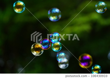 Soap bubbles floating against the background of tree shadows 106430910