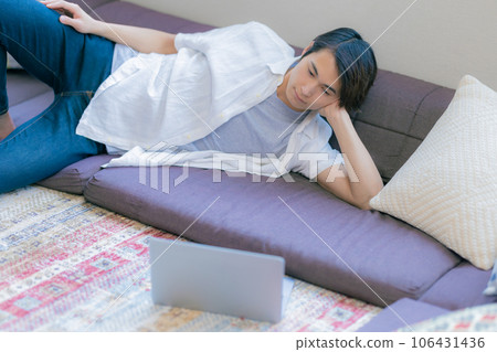Young man relaxing at home using a computer Young man relaxing at home using a computer 106431436