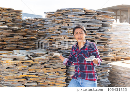 Woman seller demonstrates natural stone tiles for facade Woman seller demonstrates natural stone tiles for facade 106431833