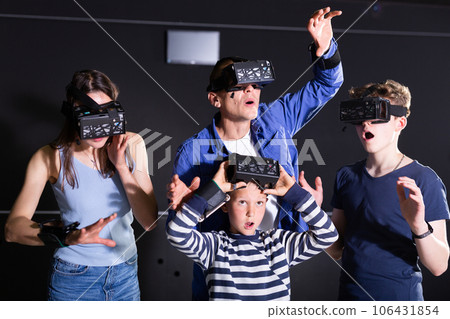 Excited teen boys with parents playing virtual reality games Excited teen boys with parents playing virtual reality games 106431854