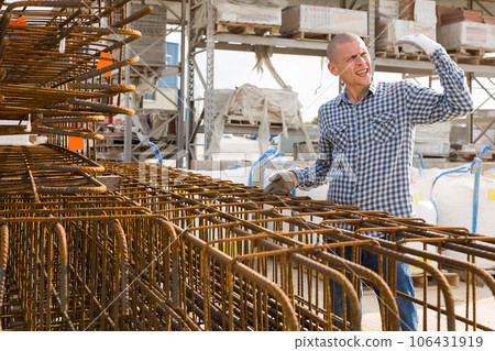 Man worker with reinforcing steel bars during work in warehouse 106431919