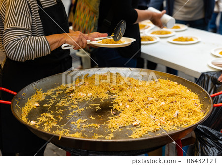 Chef serving seafood fideua into plates at street festival 106432121