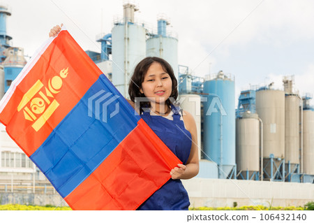 Happy asian girl in work clothes with flag of mongolia standing in front of industrial scenery 106432140
