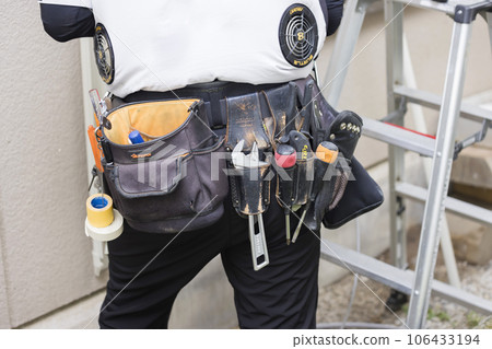 A male worker who wears waist gear and air-conditioning clothes to work Air conditioning installation work 106433194