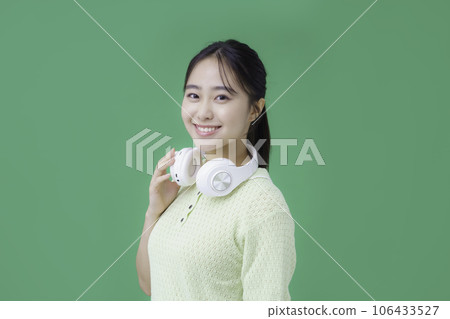 Young woman wearing green screen headphones around her neck Young woman wearing green screen headphones around her neck 106433527