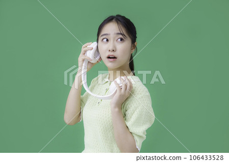 Young woman wearing green-backed headphones Young woman wearing green-backed headphones 106433528