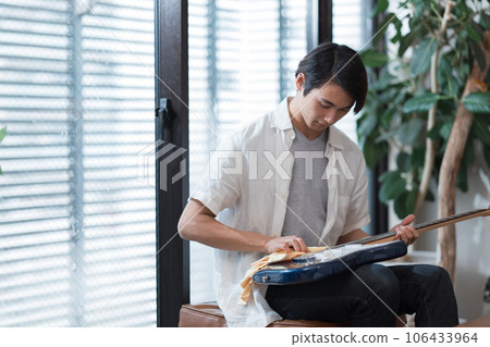 年輕人在家照顧他的吉他 年輕人在家照顧他的吉他 106433964