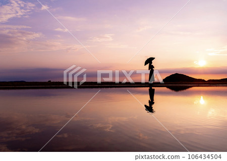 A woman walking on Chichibugahama Beach at sunset 106434504