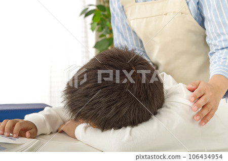 A mother snuggles with a child who seems to be having trouble studying 106434954
