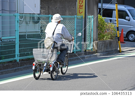 A senior riding a three-wheeled bicycle while bathing in the early spring sun A senior riding a three-wheeled bicycle while bathing in the early spring sun 106435313
