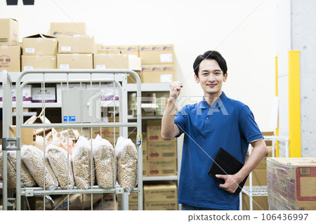 一個在倉庫工作的年輕人擺出勇敢的姿勢 一個在倉庫工作的年輕人擺出勇敢的姿勢 106436997