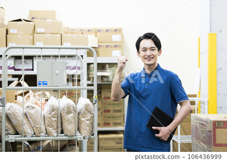 一個在倉庫工作的年輕人擺出勇敢的姿勢 一個在倉庫工作的年輕人擺出勇敢的姿勢 106436999