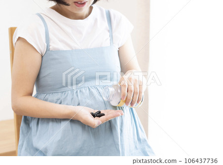 Image of a pregnant woman taking supplements 106437736