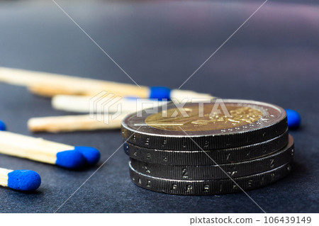 Blue matches and stack of coins on dark background macro 106439149