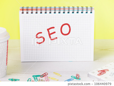 Seo the word is written on a blank sheet in a notebook standing on a table on a yellow background Seo the word is written on a blank sheet in a notebook standing on a table on a yellow background 106440979