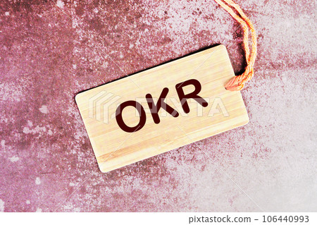 OKR, Objectives and Key Results word written on a card with a rope on an abstract background OKR, Objectives and Key Results word written on a card with a rope on an abstract background 106440993