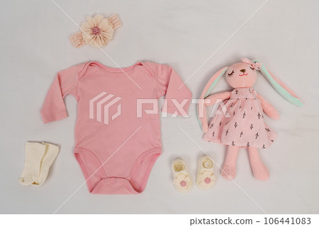 set of baby clothes and toy and accessories on white bed 106441083