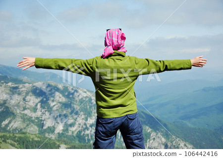 Hiker standing on the top of the mountain with raised hands Hiker standing on the top of the mountain with raised hands 106442416