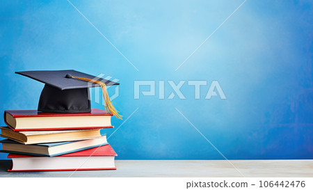 School books and graduation hat on table with blue wall background School books and graduation hat on table with blue wall background 106442476