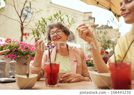 Two mature women together enjoying lunch while sitting in cafe terrace 106443230