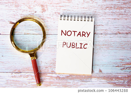 NOTARY PUBLIC text written on a notebook on wooden boards next to a magnifying glass 106443288