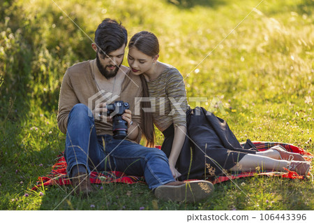 young couple sitting in nature and looking at the camera young couple sitting in nature and looking at the camera 106443396