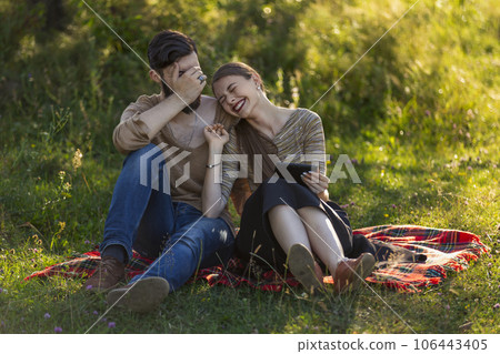 Young couple sitting in nature and looking at a tablet 106443405