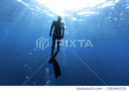 Freediver Swimming in Deep Sea With Sunrays. Freediver Swimming in Deep Sea With Sunrays. 106444210