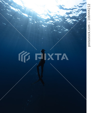 Freediver Swimming in Deep Sea With Sunrays. Freediver Swimming in Deep Sea With Sunrays. 106444212