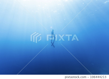 Freediver Swimming in Deep Sea With Sunrays. Freediver Swimming in Deep Sea With Sunrays. 106444213