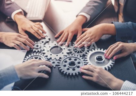People joining cog wheel on the black desk. 106444217