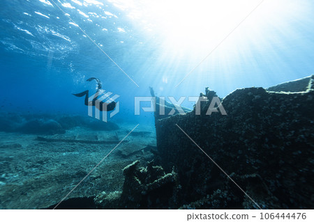 Freediver Swimming in Deep Sea and Exploring Ship Wreck. 106444476