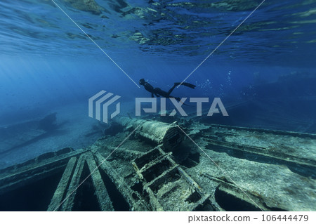 Freediver Swimming in Deep Sea and Exploring Ship Wreck. Freediver Swimming in Deep Sea and Exploring Ship Wreck. 106444479