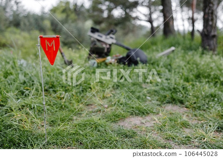 Explosive devices and a metal detector lie on the background of a forest massif. Equipment for demining the territory Explosive devices and a metal detector lie on the background of a forest massif. Equipment for demining the territory 106445028