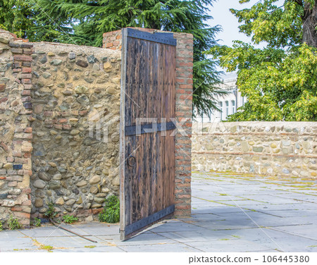 Opened wooden door and stone wall to the garden. Opened wooden door and stone wall to the garden. 106445380