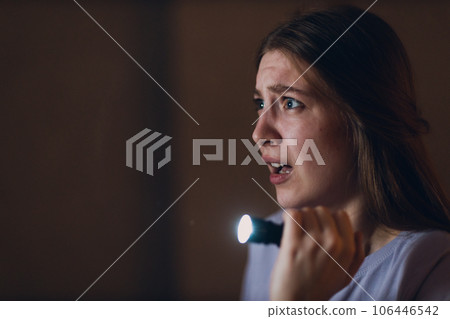 Woman scared holding hand flashlight in darkness and afraid of violence criminal robbery 106446542