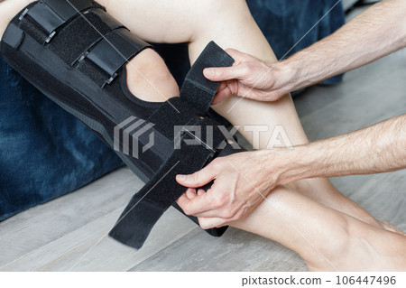 Injured knee in orthopedic bandage. Female in knee brace closeup 106447496
