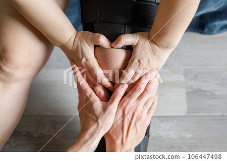 Closeup photo of injured knee in orthopedic bandage. Female in knee brace  and doctor hands 106447498