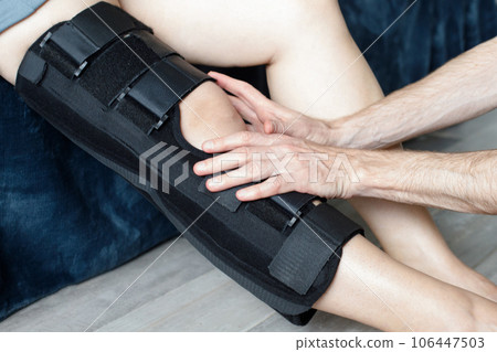 Closeup female leg in grey leggings dressed in knee brace to help promote recovery of bones 106447503