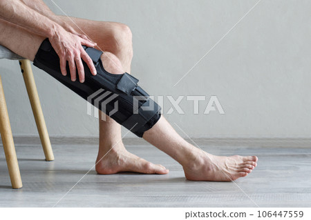 Knee Brace on male leg on grey background. Orthopedic Anatomic Orthosis. Braces for knee fixation Knee Brace on male leg on grey background. Orthopedic Anatomic Orthosis. Braces for knee fixation 106447559