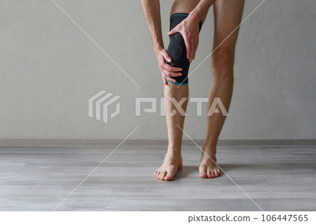 Knee Support Brace on male leg on grey background. Elastic orthopedic orthosis.  106447565