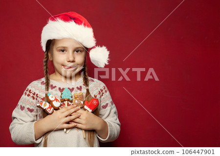 Christmas child girl. Kid holds gingerbread cookie Snowman, Santa Claus reindeer and Xmas tree  106447901