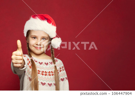 Christmas child girl showing thumb up on red background, Christmas and New Year portrait 106447904