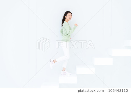 A young woman standing up the stairs 106448110