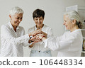 Three confident mature women stacking hands and smiling. 106448334
